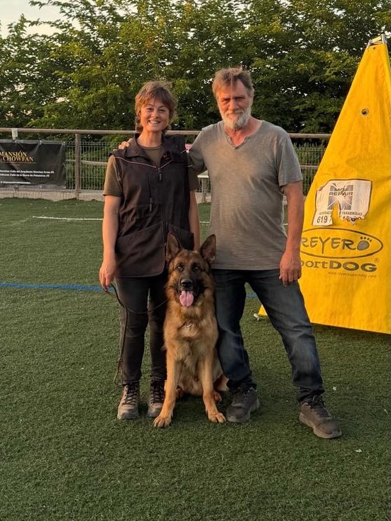 Pareja con su pastor alemán al atardecer en la pista de Dogquijote